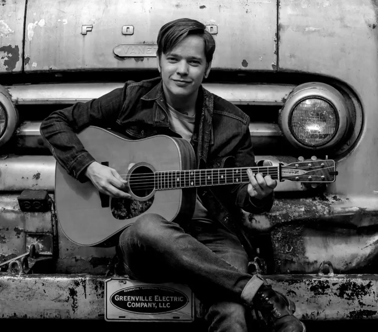 Billy Strings, playing guitar in front of a truck