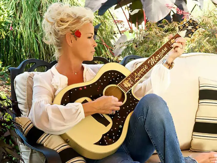 Lorrie Morgan playing a guitar while sitting