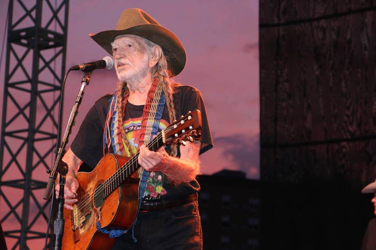 Willie Nelson with guitar and mike performing at a live concert