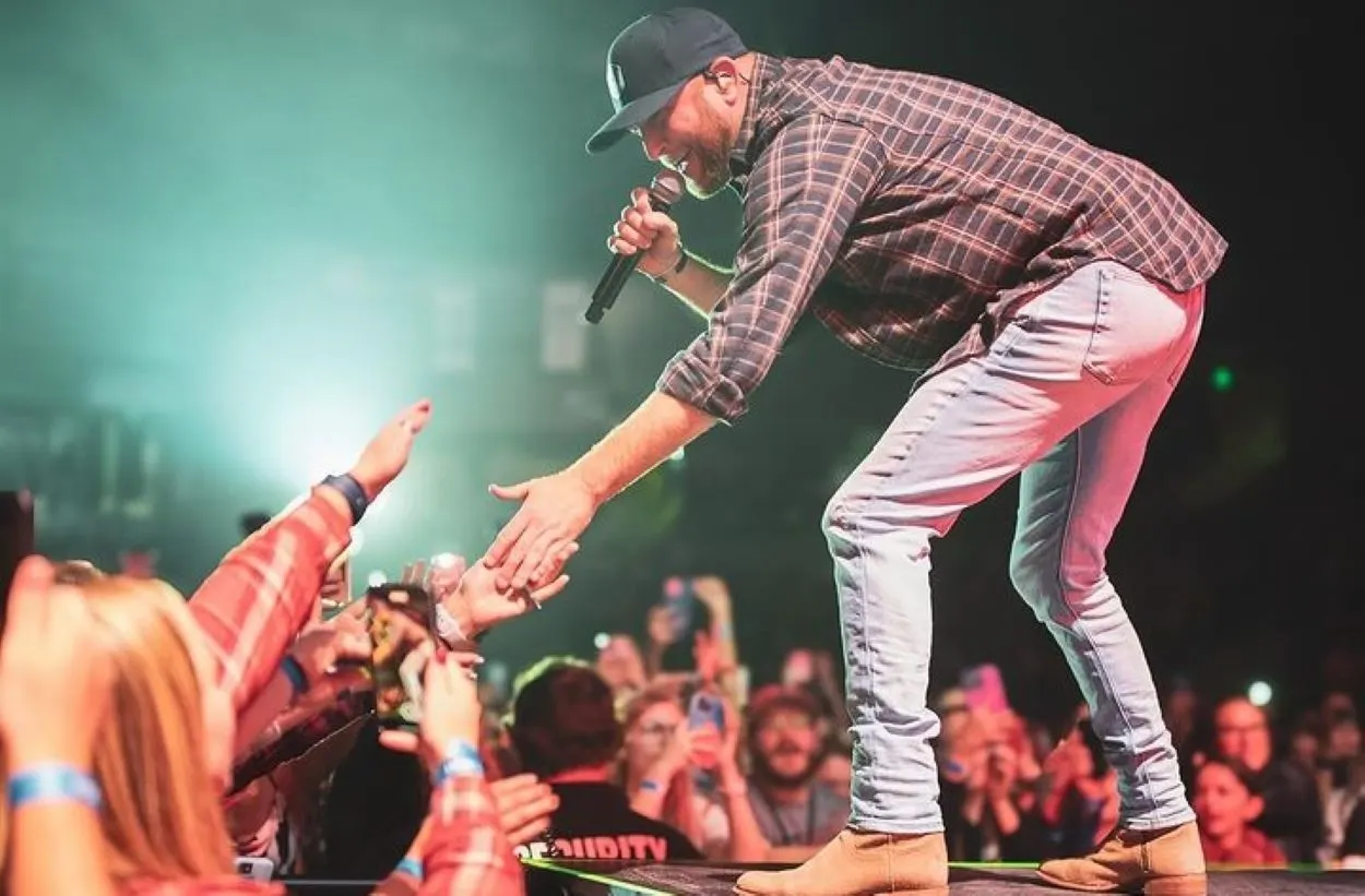 Cole Swindell performing and shaking hands with the audience