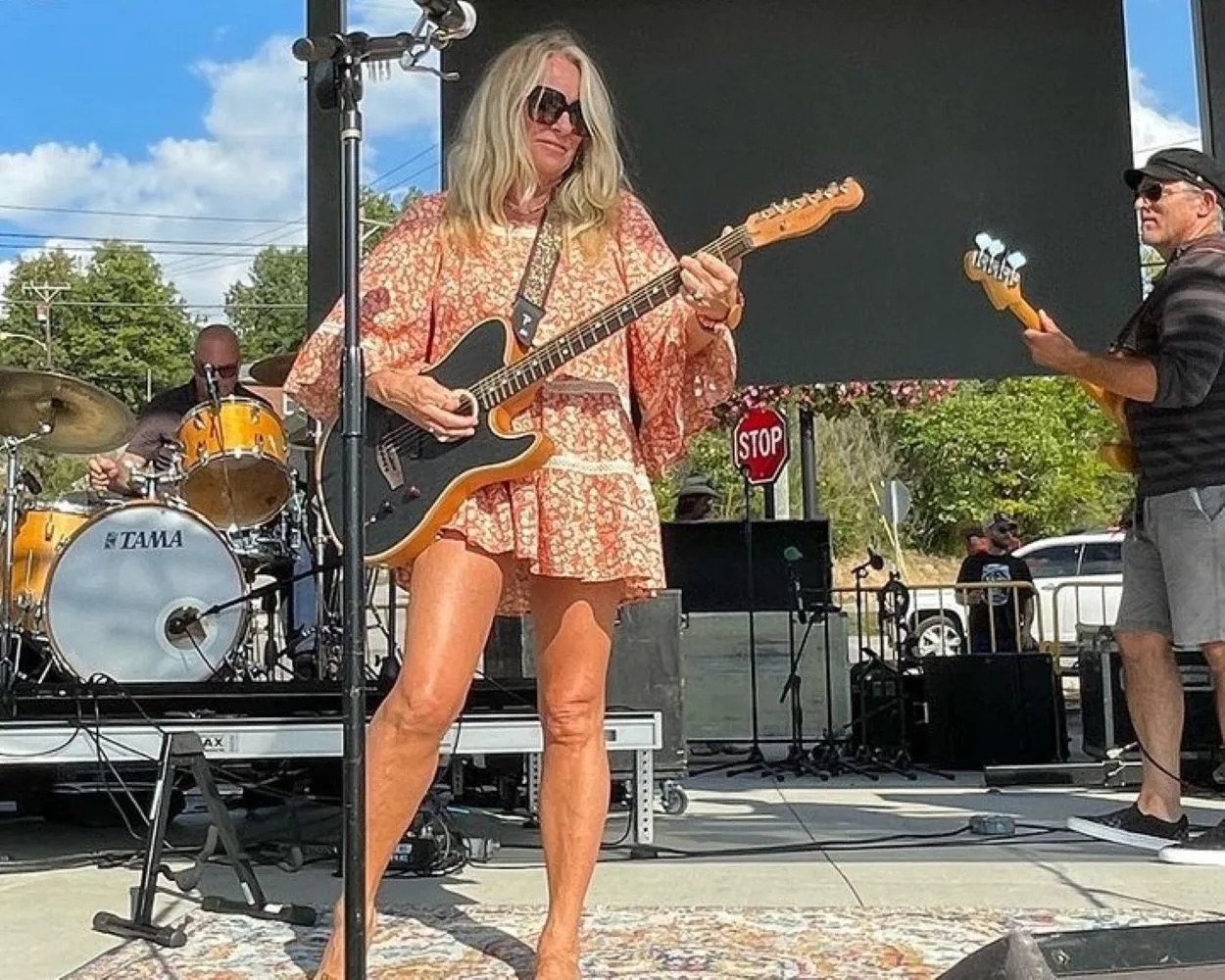 Deana Carter on stage playing her guitar with a man on the back.