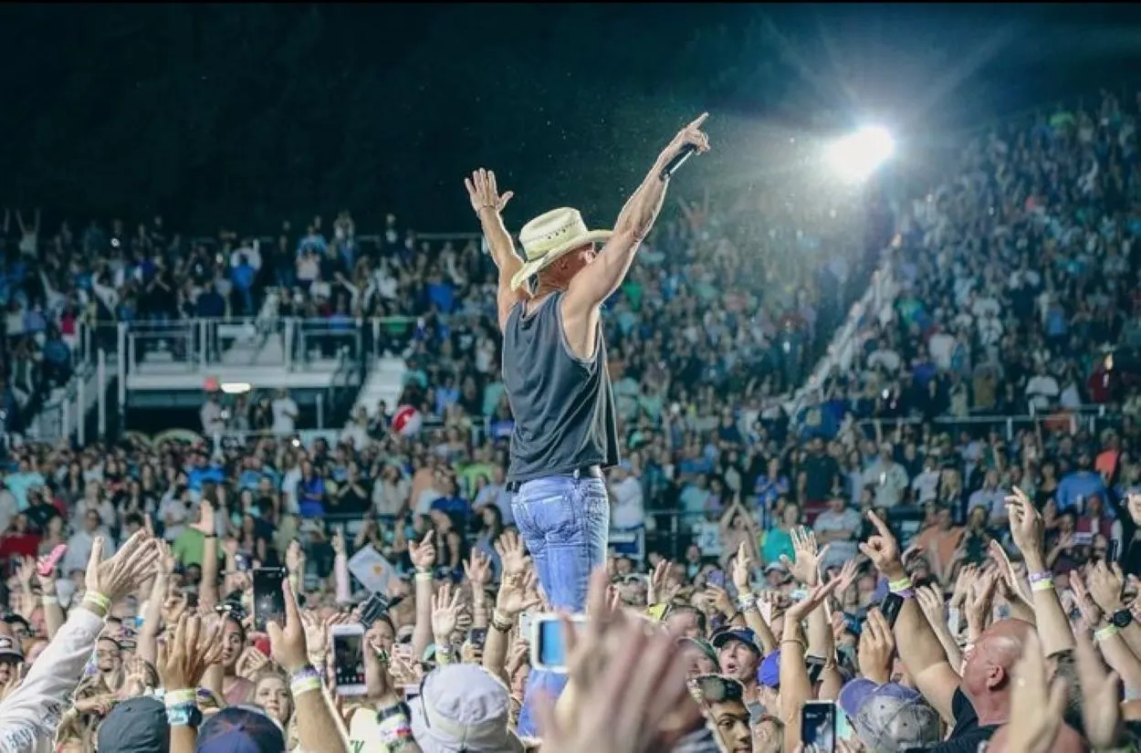 Kenny Chesney performing with a crowd around him.