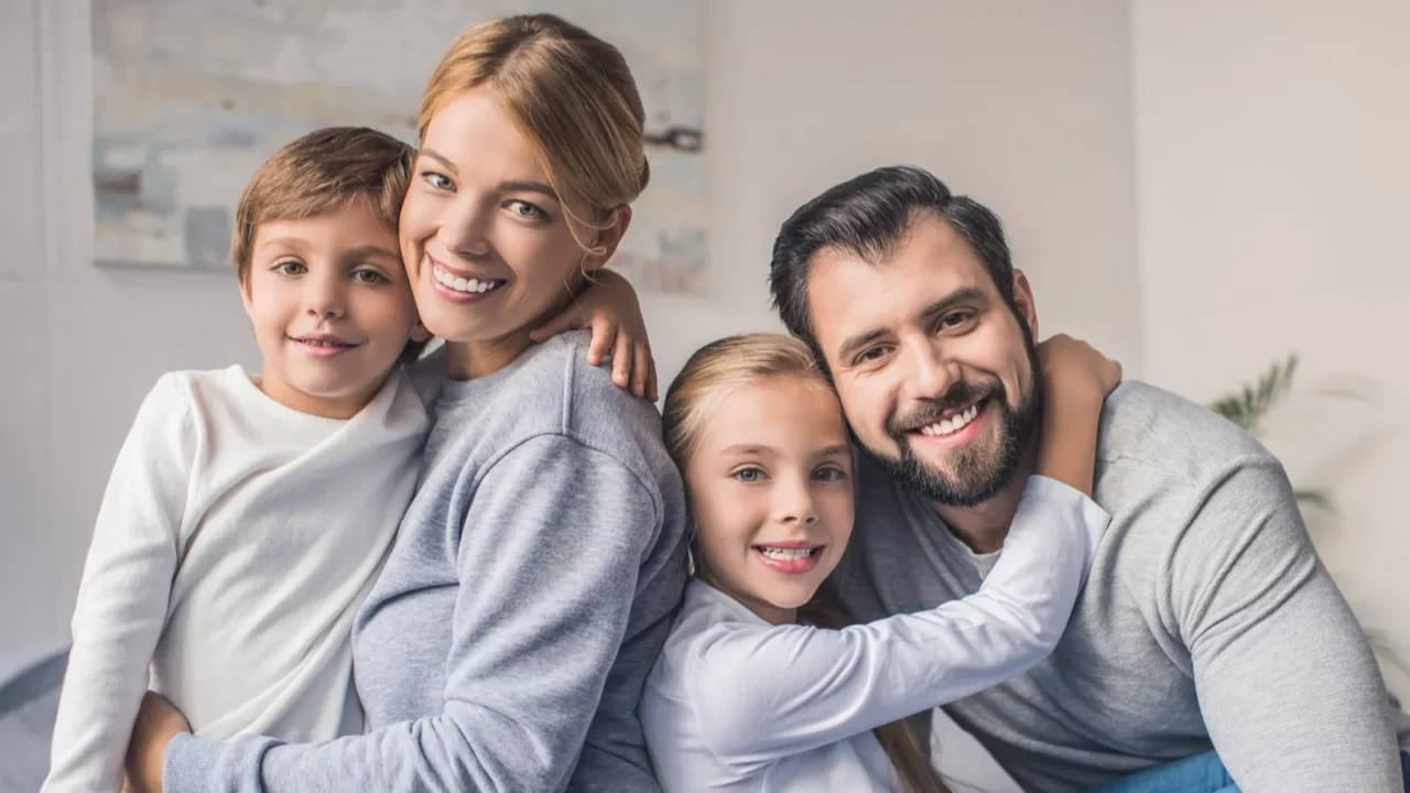 A happy family of four smiling and hugging.